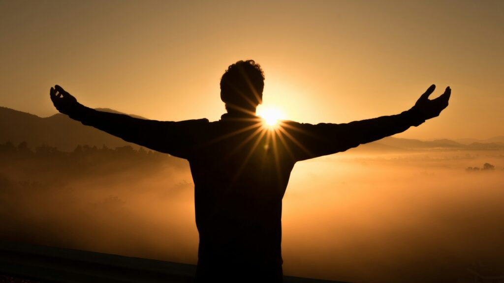 silhouette photo of man on cliff during sunset