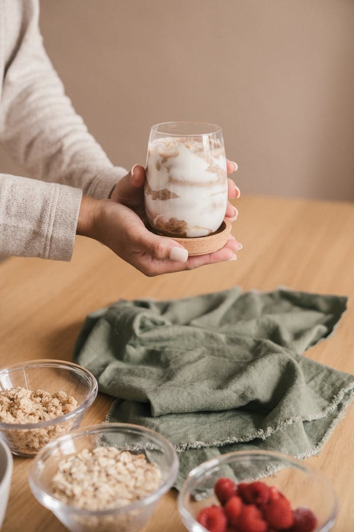 A delicious yogurt parfait with granola and fresh raspberries on a wooden table.