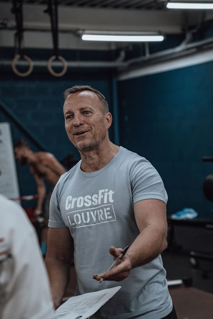 a man in a crossfit t - shirt holding a piece of paper