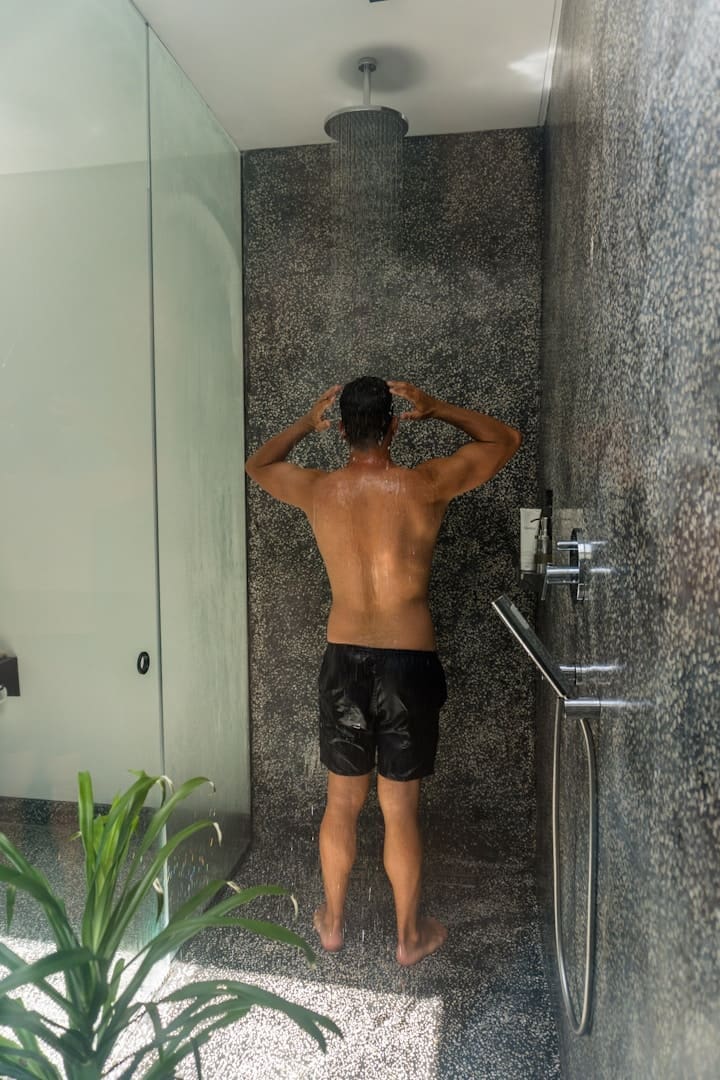 A man standing in front of a shower in a bathroom