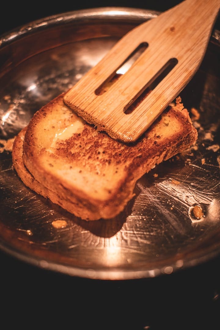 Delicious homemade toast being cooked with a wooden spatula.