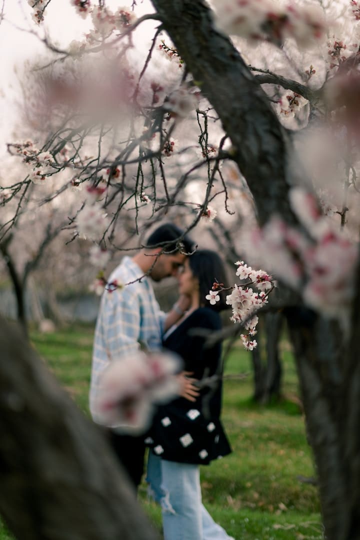 a man and a woman standing under a tree