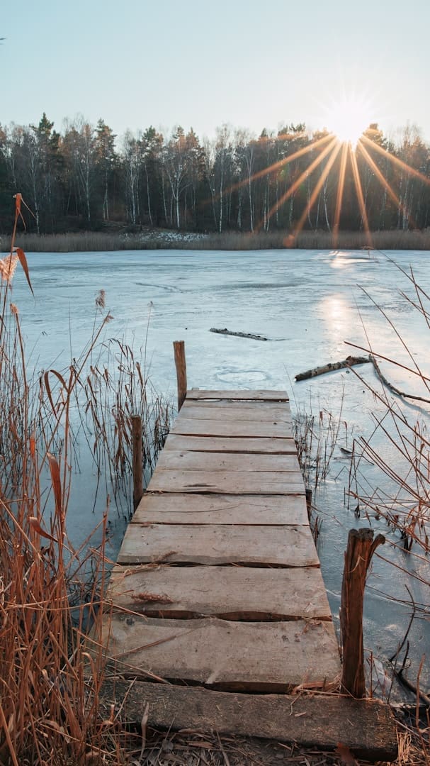 Wooden pier on frozen lake at sunrise